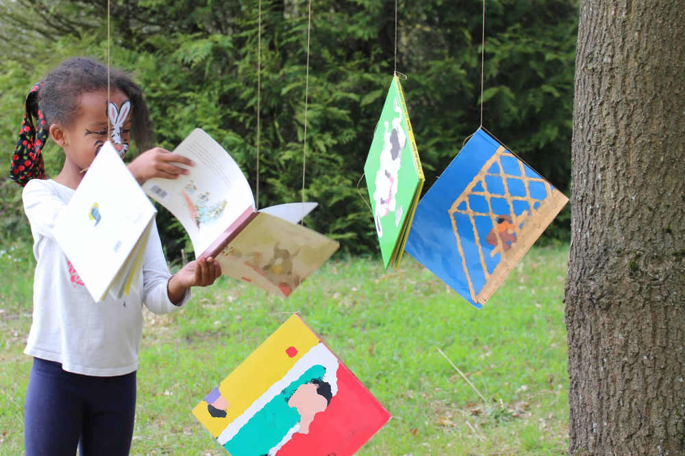 Enfant avec des livres accrochés dans un arbre