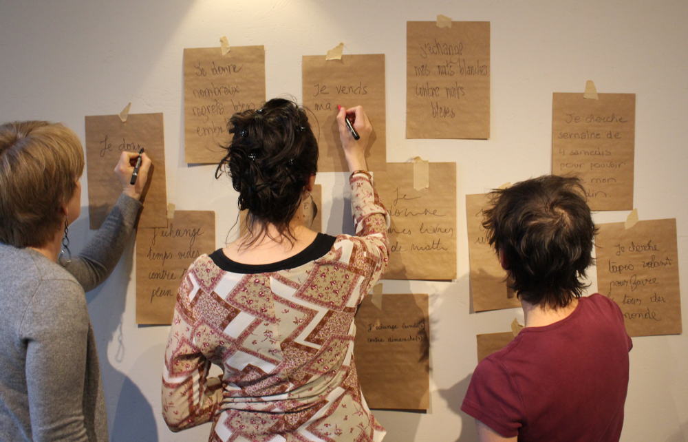 personnes écrivant sur des feuilles sur un mur